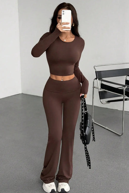 Person wearing a brown outfit taking a mirror selfie in a minimalistic room.